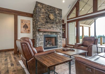 A custom living room with large windows and a stone fireplace.
