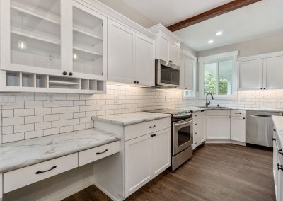 A white kitchen with wood floors and white cabinets.