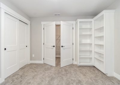 A white closet with bookshelves and a door.