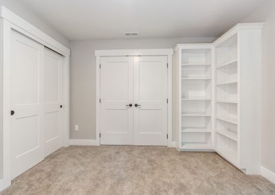 A white closet with bookshelves and shelves.