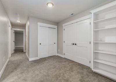 A hallway with white closets and bookshelves.