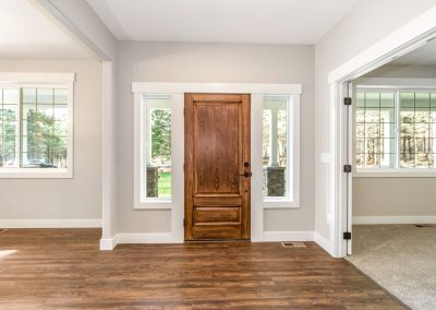 An empty living room with hardwood floors and a wooden door.