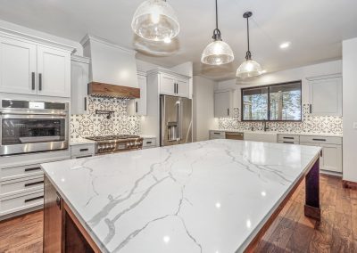 A kitchen with marble counter tops and stainless steel appliances.