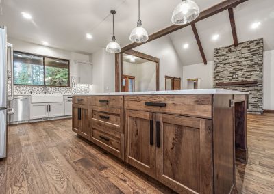 A kitchen with wood floors and a stone fireplace.