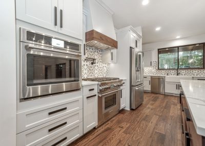 A white kitchen with stainless steel appliances and hardwood floors.