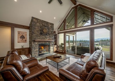 A living room with large windows and a stone fireplace.
