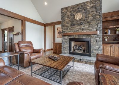 A living room with a stone fireplace and leather furniture.
