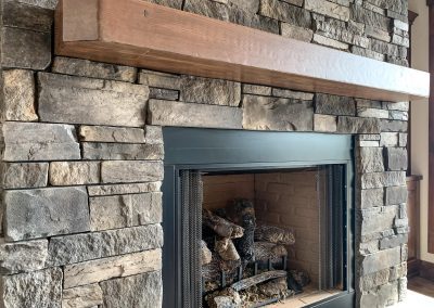A stone fireplace with a wood mantel.
