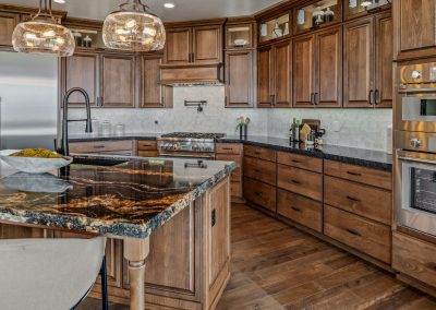 A kitchen with wood cabinets and marble counter tops.