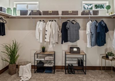 A walk in closet with clothes hanging on racks.