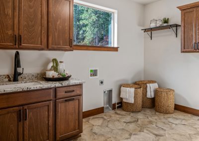 A laundry room with wooden cabinets and a window.