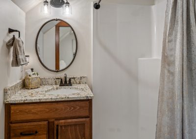 A bathroom with a sink, shower, and mirror.