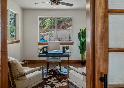 A home office with a cowhide rug and a fan.