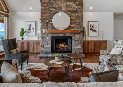 A living room with a stone fireplace and cowhide rug.