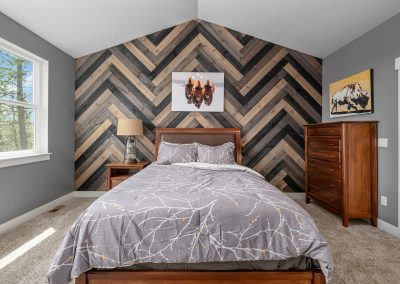 A bedroom with a wood chevron wall.