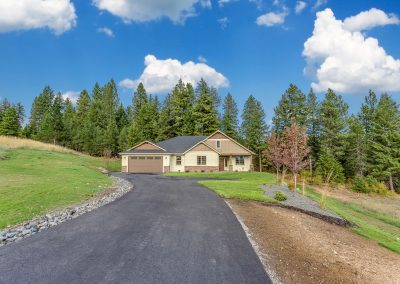 A home with a driveway leading to a wooded area.