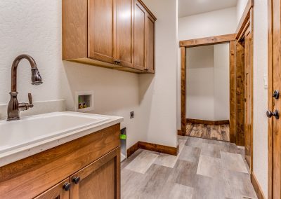 A laundry room with wood cabinets and a sink.