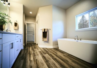 A bathroom with wood floors and a tub.
