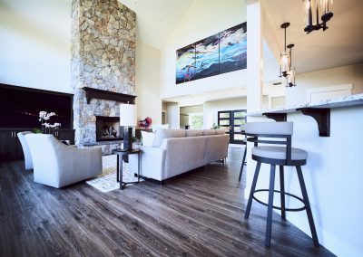 A living room with hardwood floors and a stone fireplace.