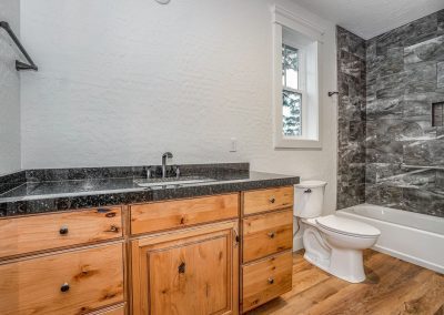 A bathroom with wood floors and tiled walls.