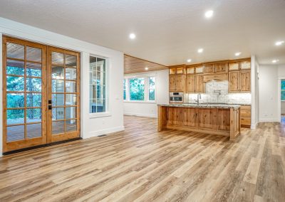 An empty kitchen with wood floors and a sliding glass door.