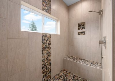 A tiled shower with a bench and window.