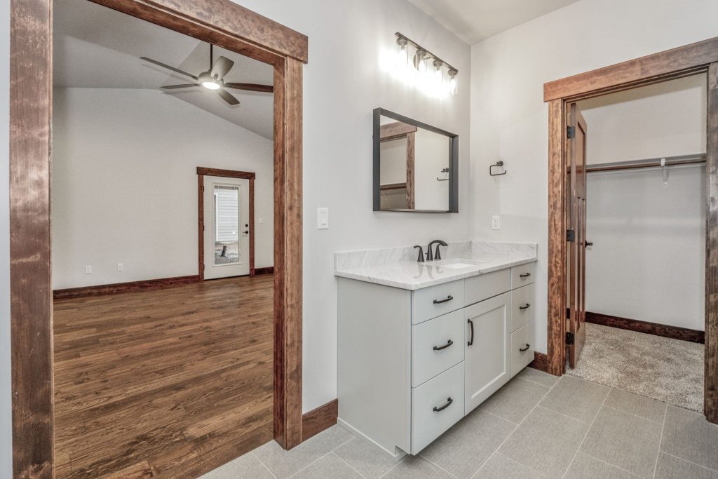 A bathroom with wood floors and a ceiling fan.