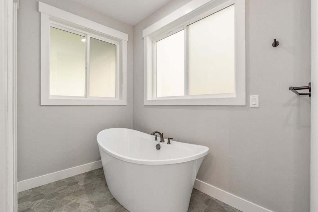 A white bathtub in a bathroom with gray walls.