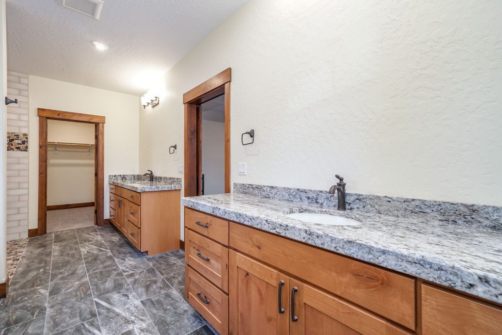 A bathroom with granite counter tops and wood cabinets.