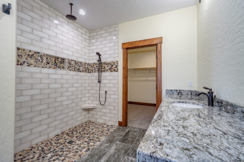 A bathroom with granite counter tops and a shower.