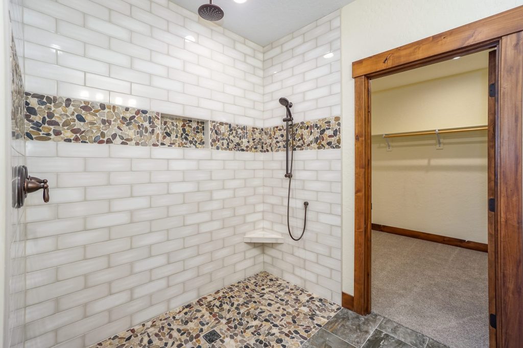 A bathroom with a tiled shower and a walk in closet.