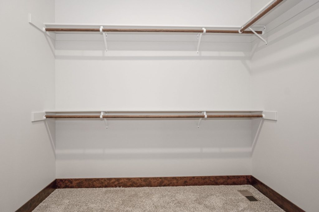 A white closet with wooden shelves and a wooden floor.