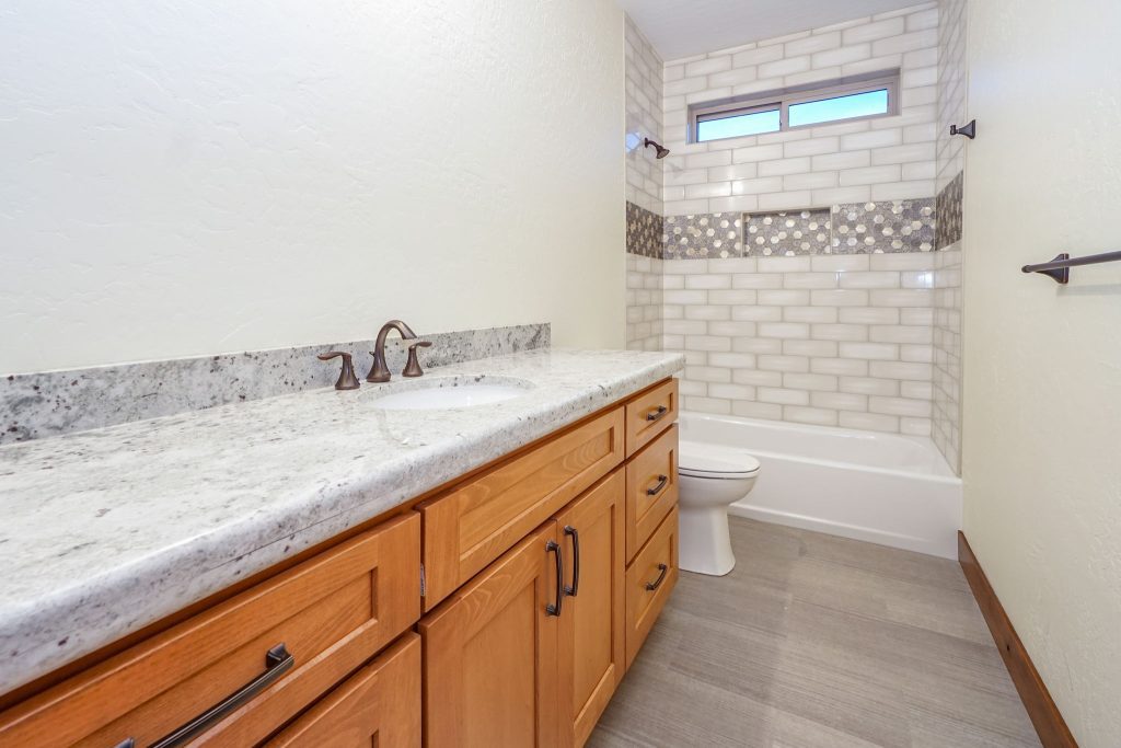 A bathroom with white cabinets and granite counter tops.