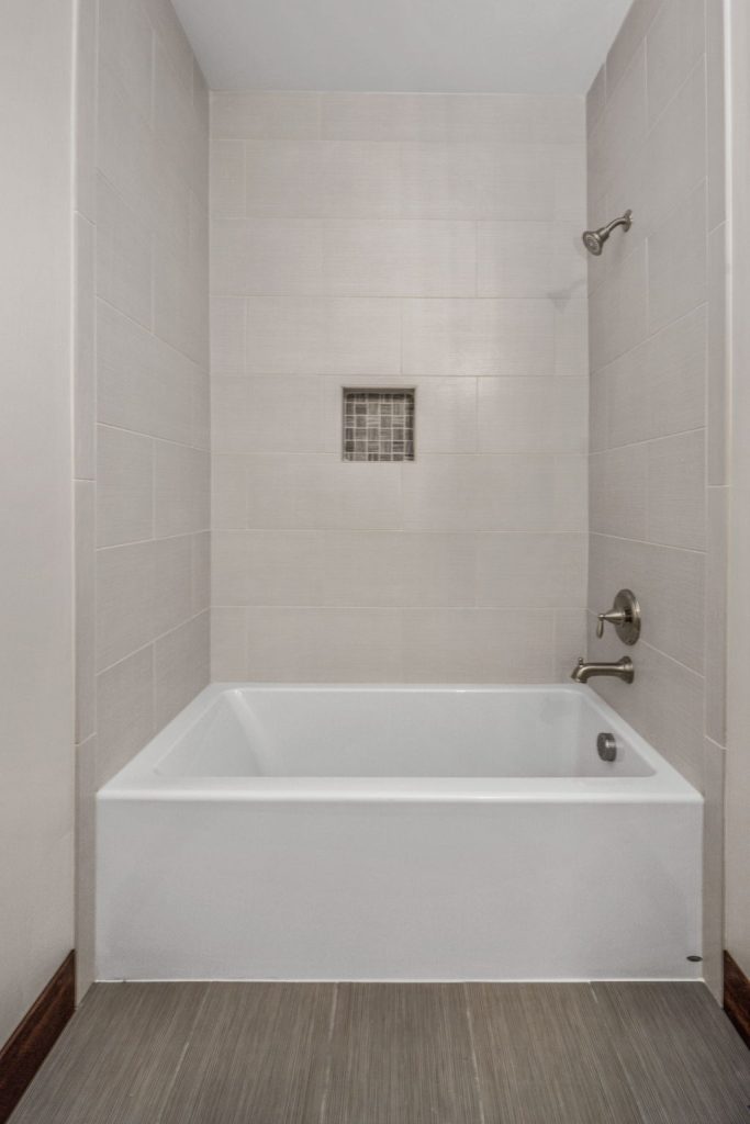 A white bathtub in a bathroom with tile floors.