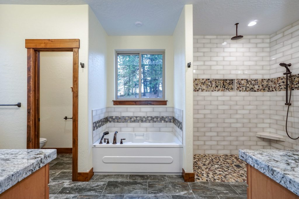 A bathroom with granite counter tops and a tub.