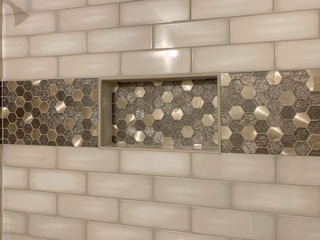 A white tiled shower with a hexagonal tile pattern.