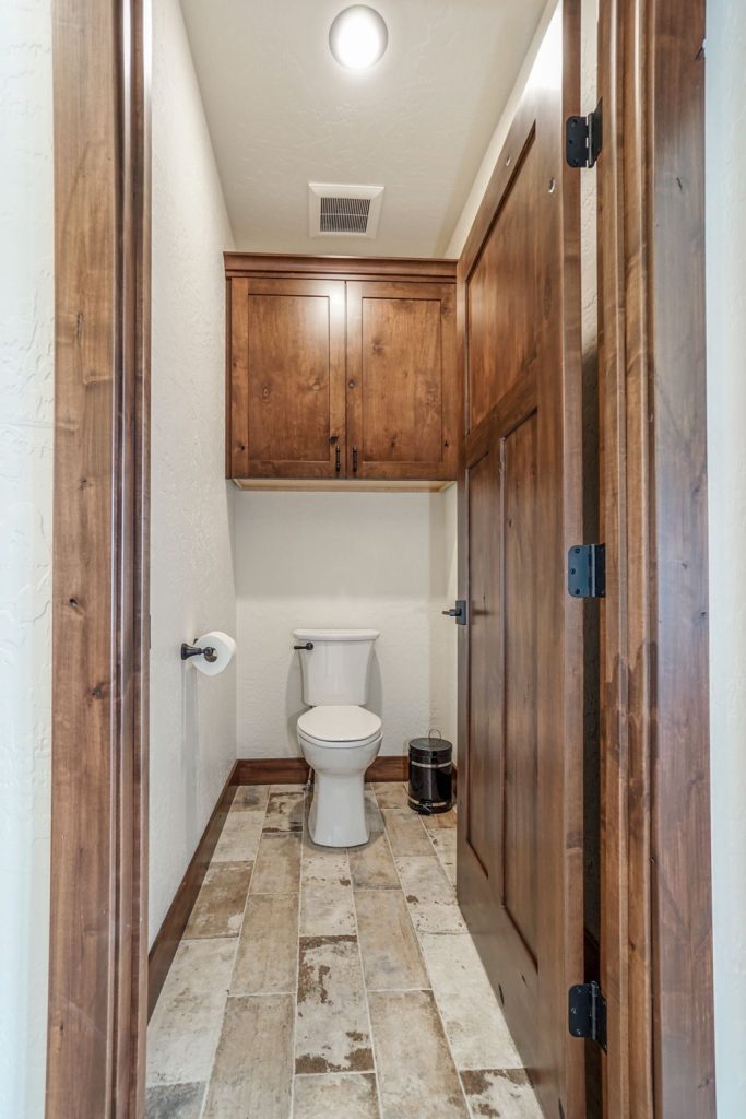 A bathroom with wooden cabinets and a toilet.