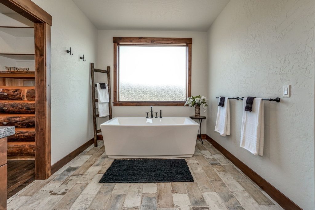A bathroom with wood floors and a tub.