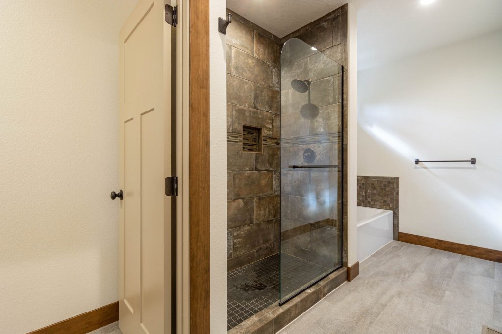 A bathroom with a glass shower stall and wooden floors.