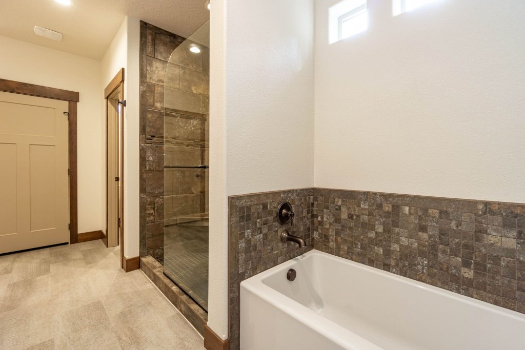 A bathroom with a walk in shower and a tub.