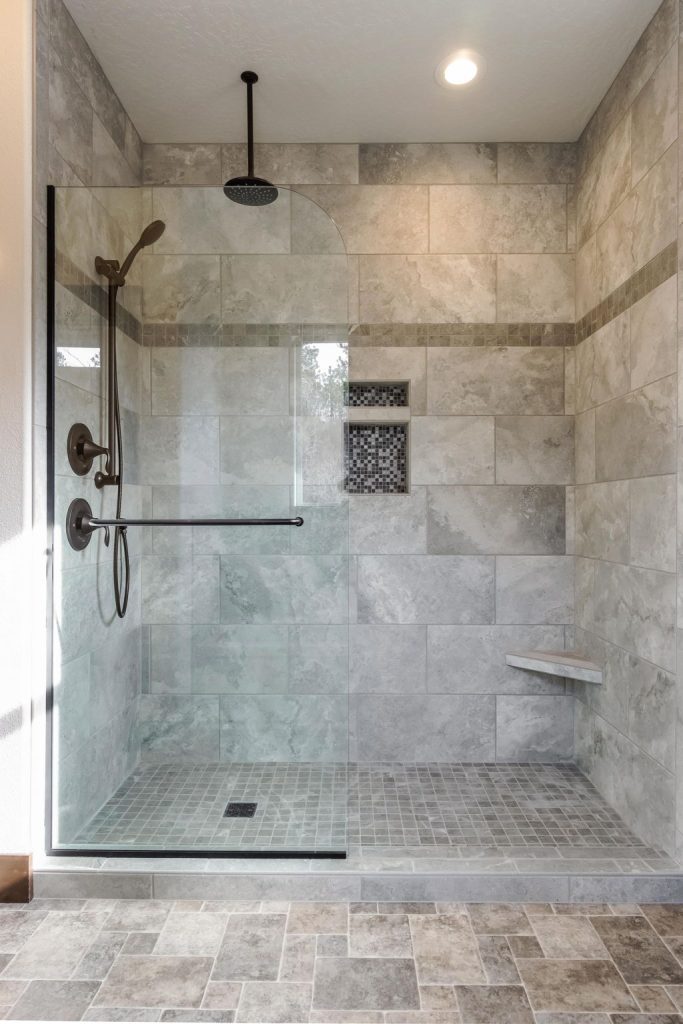 A bathroom with a glass shower stall and tile floors.