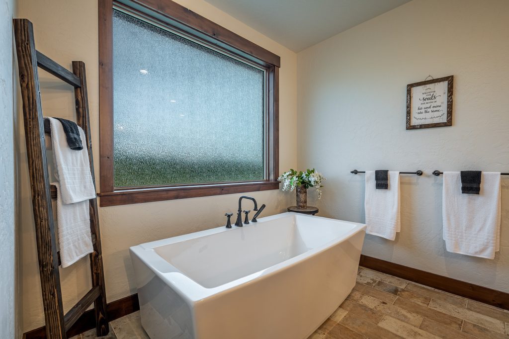 A bathroom with a white tub and window.