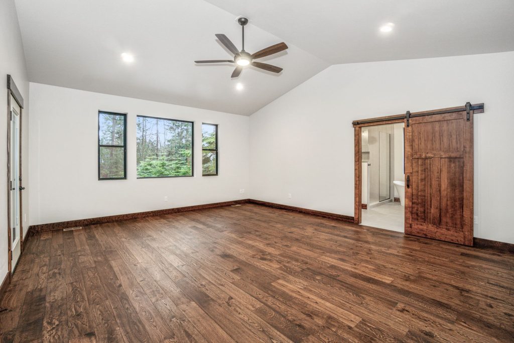 An empty room with wood floors and a ceiling fan.