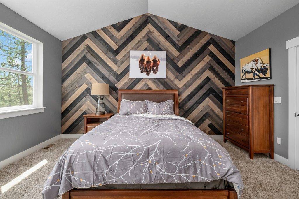 A bedroom with a wood chevron wall.