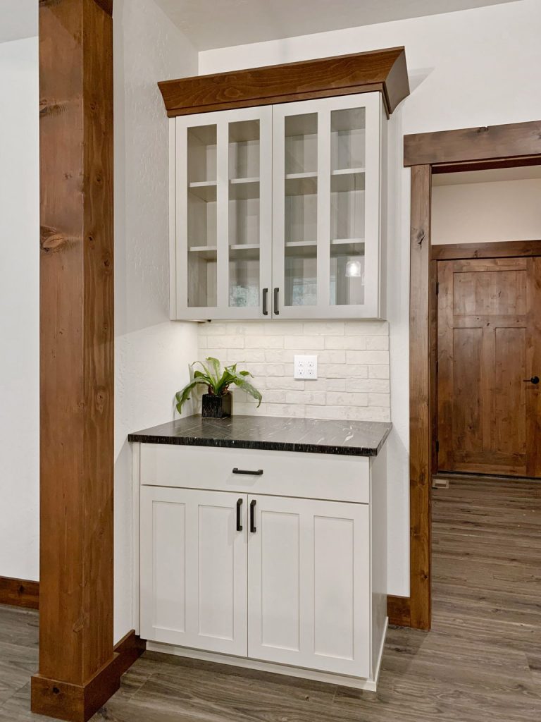 A kitchen with white cabinets and wood beams.