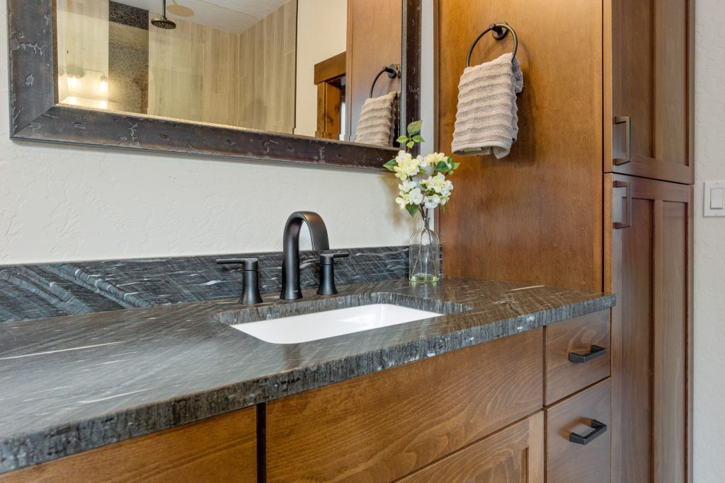 A bathroom with wooden cabinets and a marble counter top.