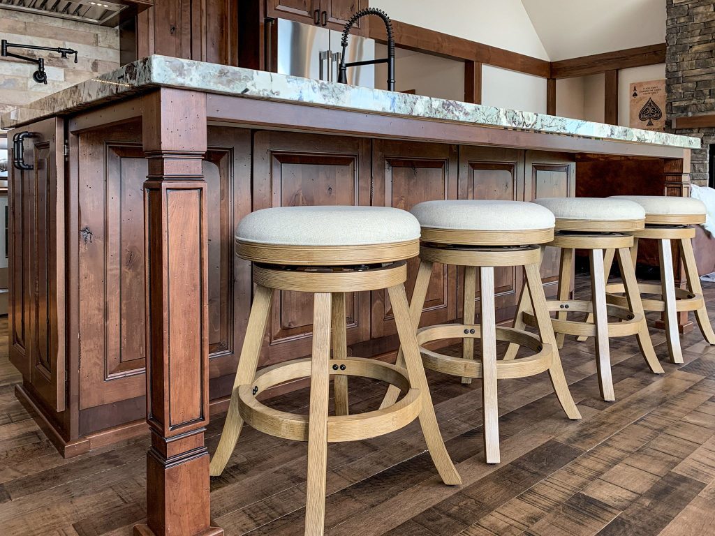 Four bar stools in a kitchen with wood floors.