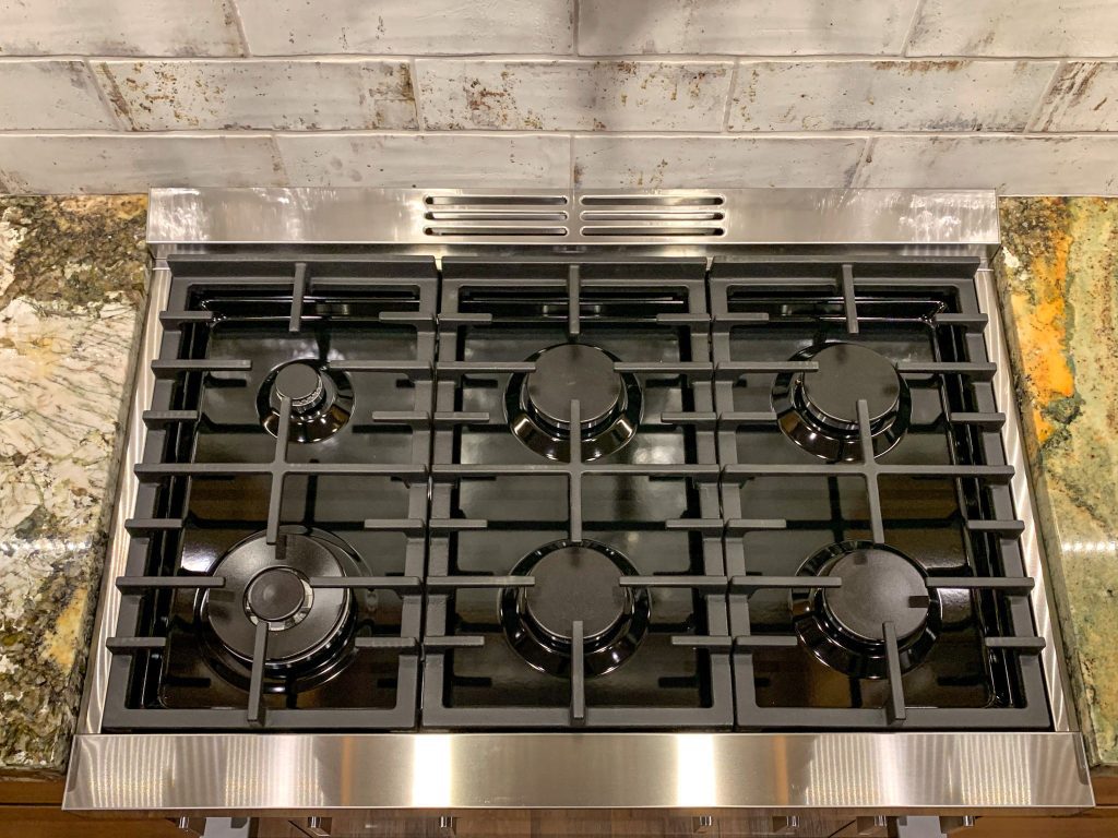 A stainless steel stove top with four burners.
