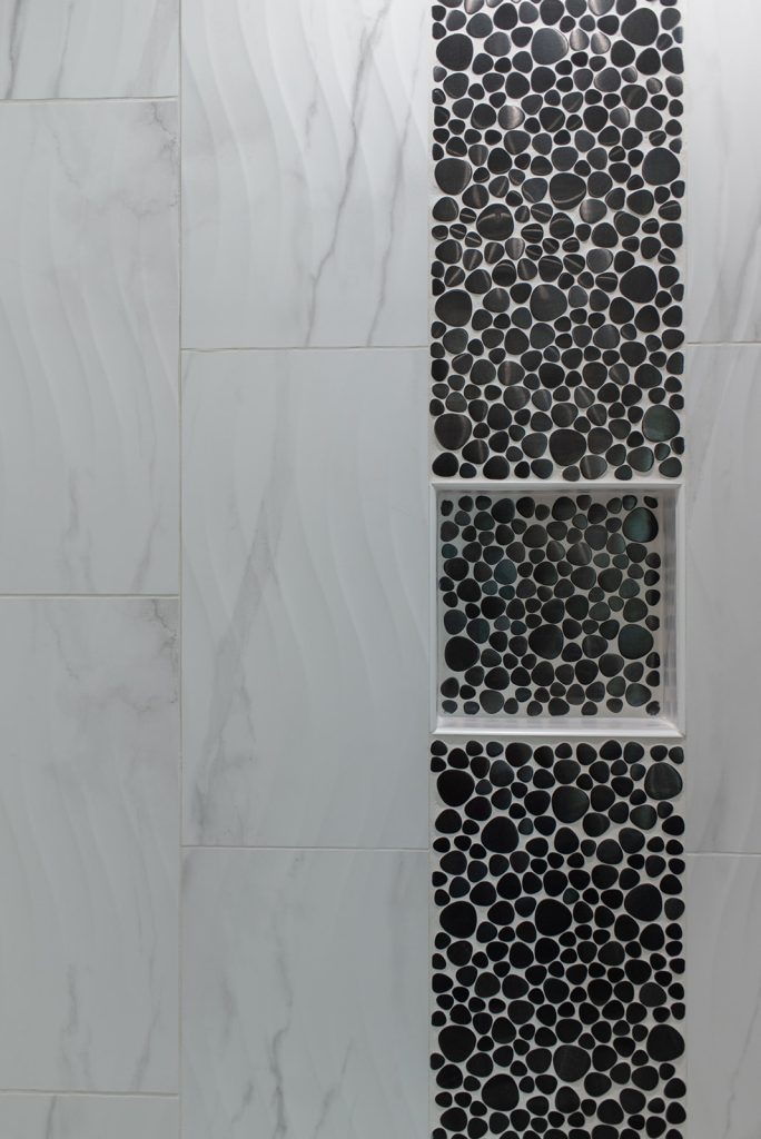 A bathroom with a black and white tiled shower.