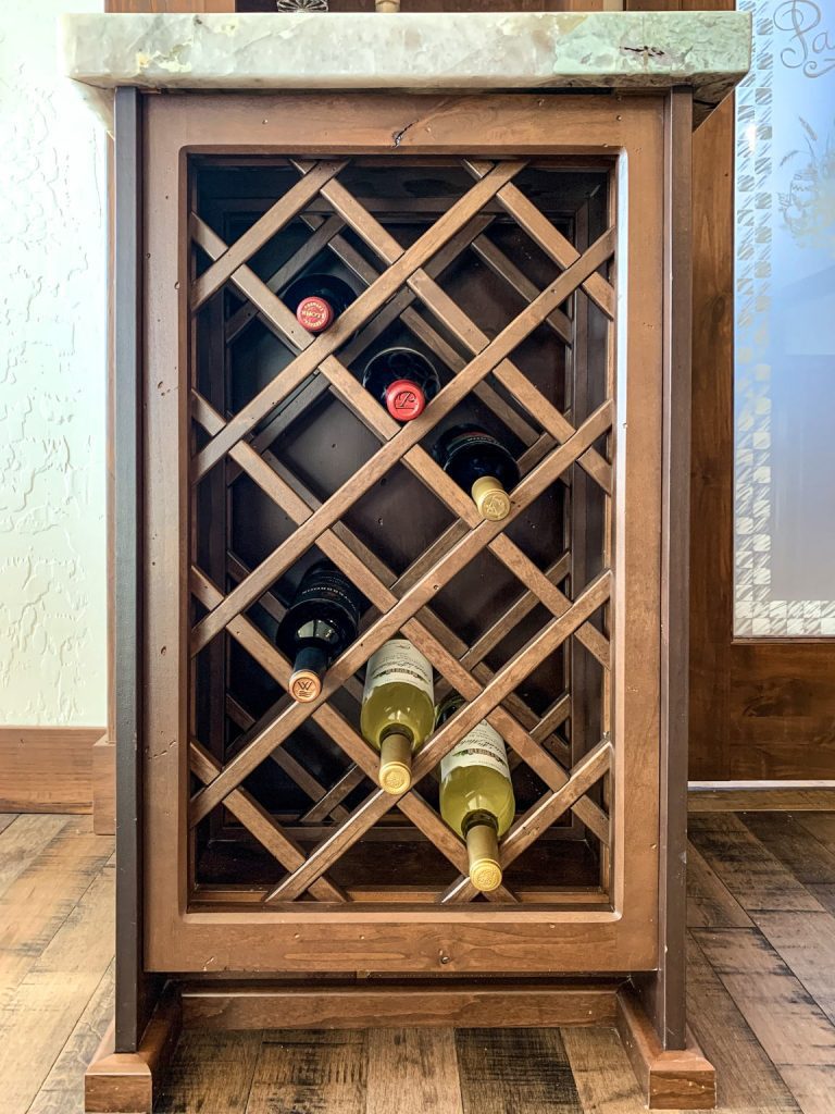 A wooden wine rack with bottles in it.